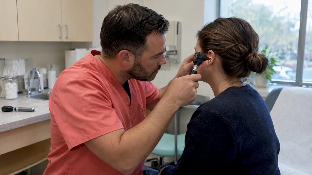 Clinician examining an ear with an otoscope