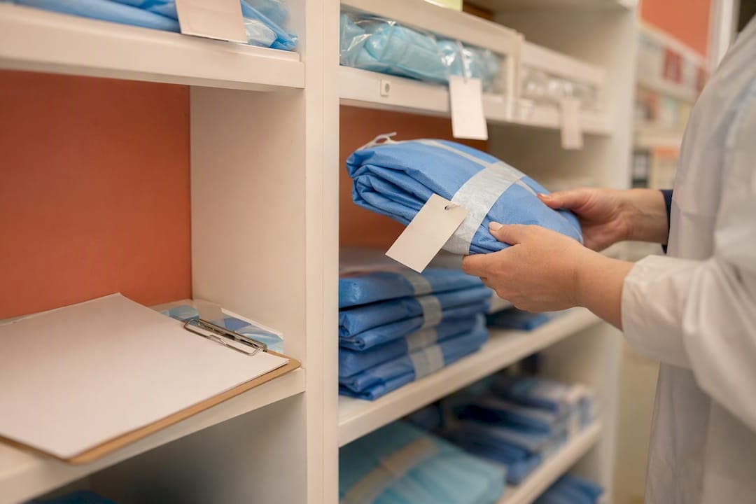 Hands selecting reusable isolation gowns in storeroom